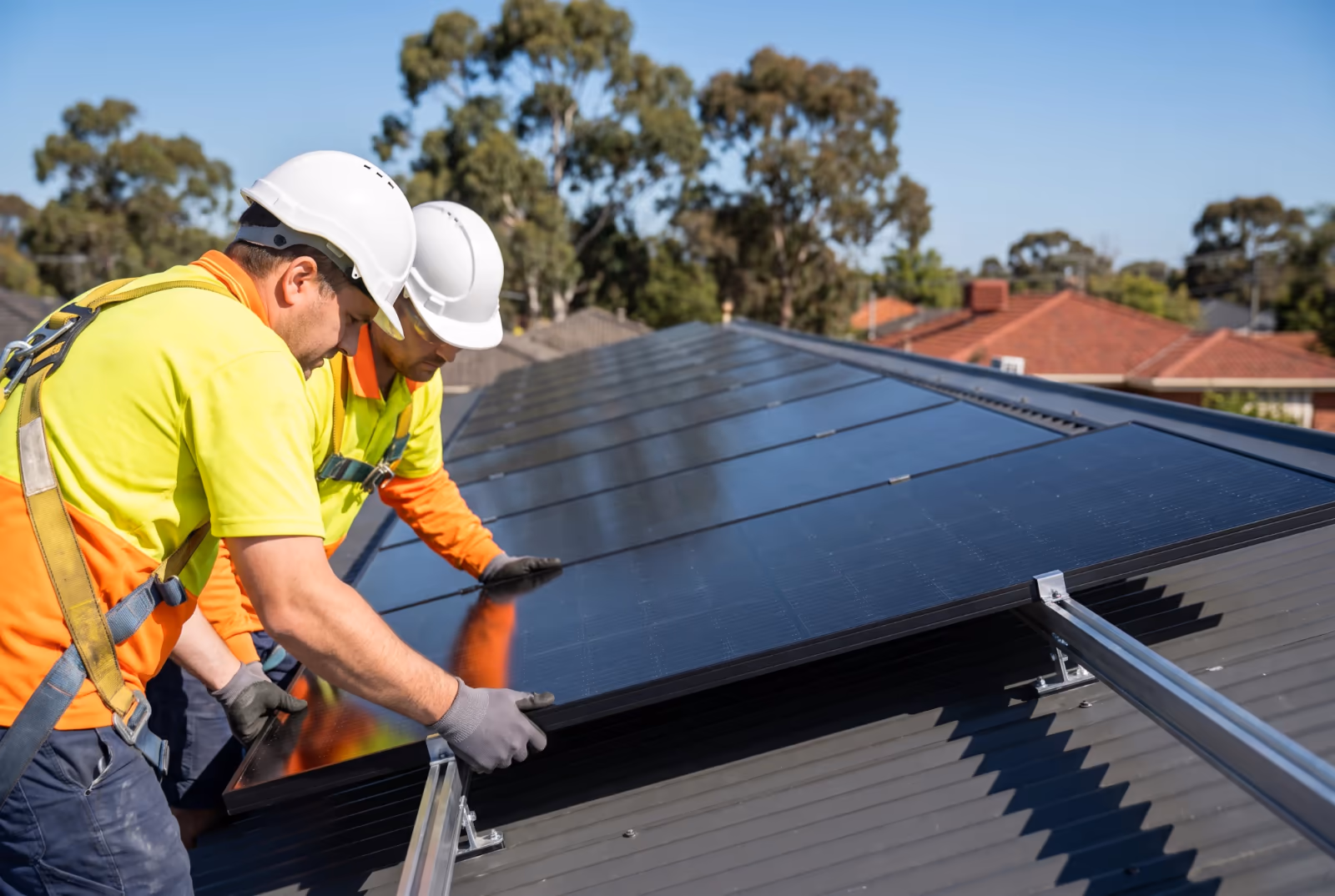 Two accredited installers fitting black solar panels to a Colorbond roof